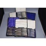 Seven assorted cased sets of silver handled tea knives including pistol handled.