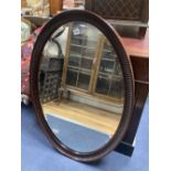 A 1920's oval-framed mahogany wall mirror, width 70cm, height 100cm