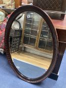 A 1920's oval-framed mahogany wall mirror, width 70cm, height 100cm