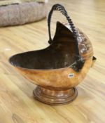 An Arts & Crafts planished copper coal scuttle, with wrought iron handle