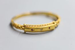 An Edwardian 15ct gold and gypsy set ruby and diamond three stone hinged bangle, gross 11.1 grams (