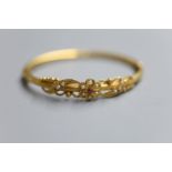 A late Victorian yellow metal, ruby and seed pearl set hinged bangle, gross 10.6 grams.CONDITION: