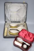 A cased George V silver four piece mirror and brush set and an associated comb(a.f.) and a cased