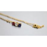A yellow metal, ruby, diamond and sapphire set line pendant, 14mm, on a yellow metal chain, 38cm,