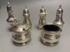 A George V three piece silver condiment set, Birmingham, 1935 and three other silver pepperettes,