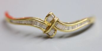 The top section only, of a yellow metal and graduated baguette cut diamond set hinged bangle,