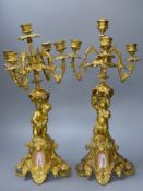A pair of 19th century French ormolu 'cherub' candelabra, with porcelain plaques to base, height