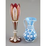 A Bohemian blue and white overlaid glass jug and a similar ruby and white overlaid glass vase,