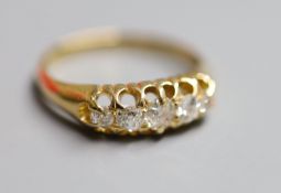 An early 20th century 18ct gold and graduated five stone diamond set half hoop ring, size P, gross 4