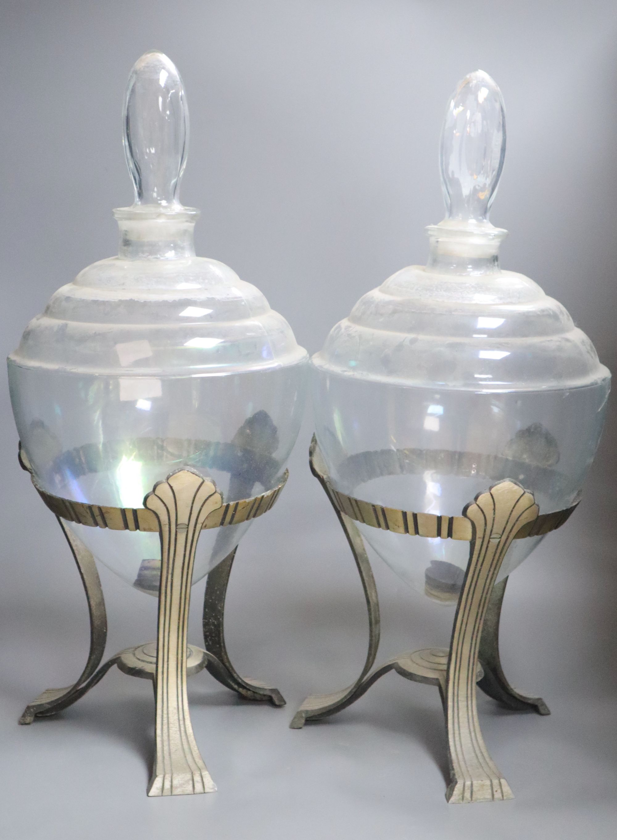 A pair of glass jars with covers on aluminium stands