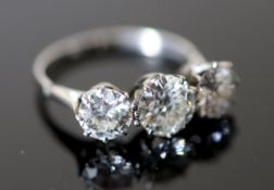 A platinum and three stone diamond ring, the central stone weighing approximately 1.20ct and the two