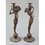 After Edward Francis McCartan (1879-1947). A pair of Art Nouveau bronze candlesticks, modelled as