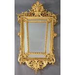 A Louis XIV style carved giltwood wall mirror, with putto mask, fruit and foliate scroll crest,