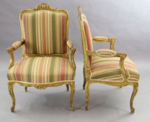 A pair of French gilt beech fauteuils, with moulded foliate scroll carved frames and cabriole