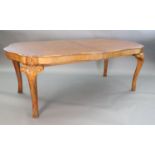 A Queen Anne style burr walnut extending dining table, the shaped top with moulded leaf carved