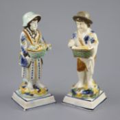 A pair of Prattware figures of fruit and biscuit street vendors, c.1790-1800, on square bases,