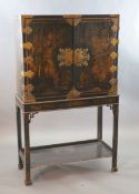 A late 17th century japanned cabinet on later stand with two doors decorated with a chinoiserie