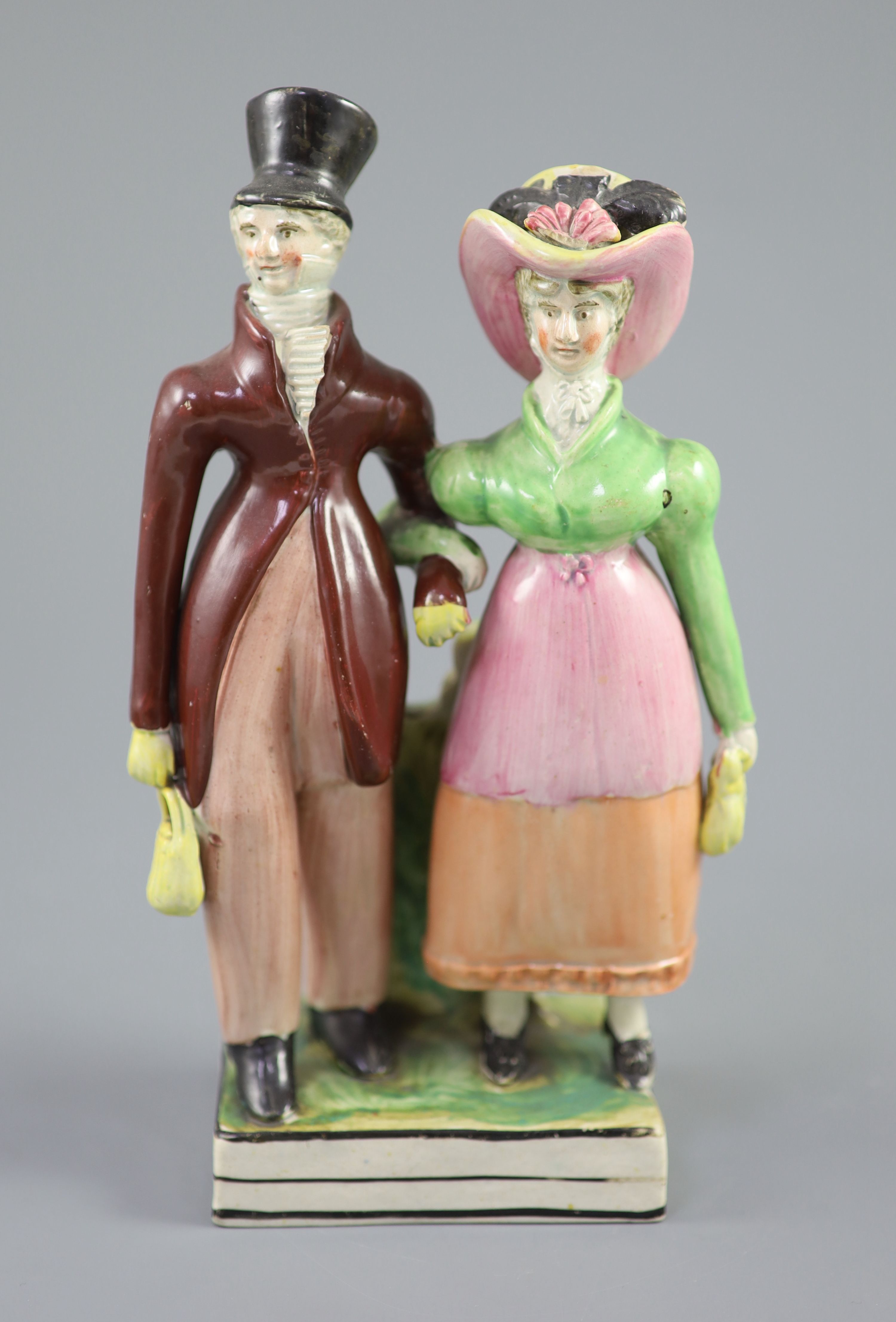 A Staffordshire pearlware group of a Dandy and Dandizette, c.1820, standing before rockwork on a