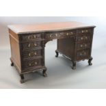 An Edwardian foliate carved mahogany serpentine kneehole desk, with gilt brown skiver, central