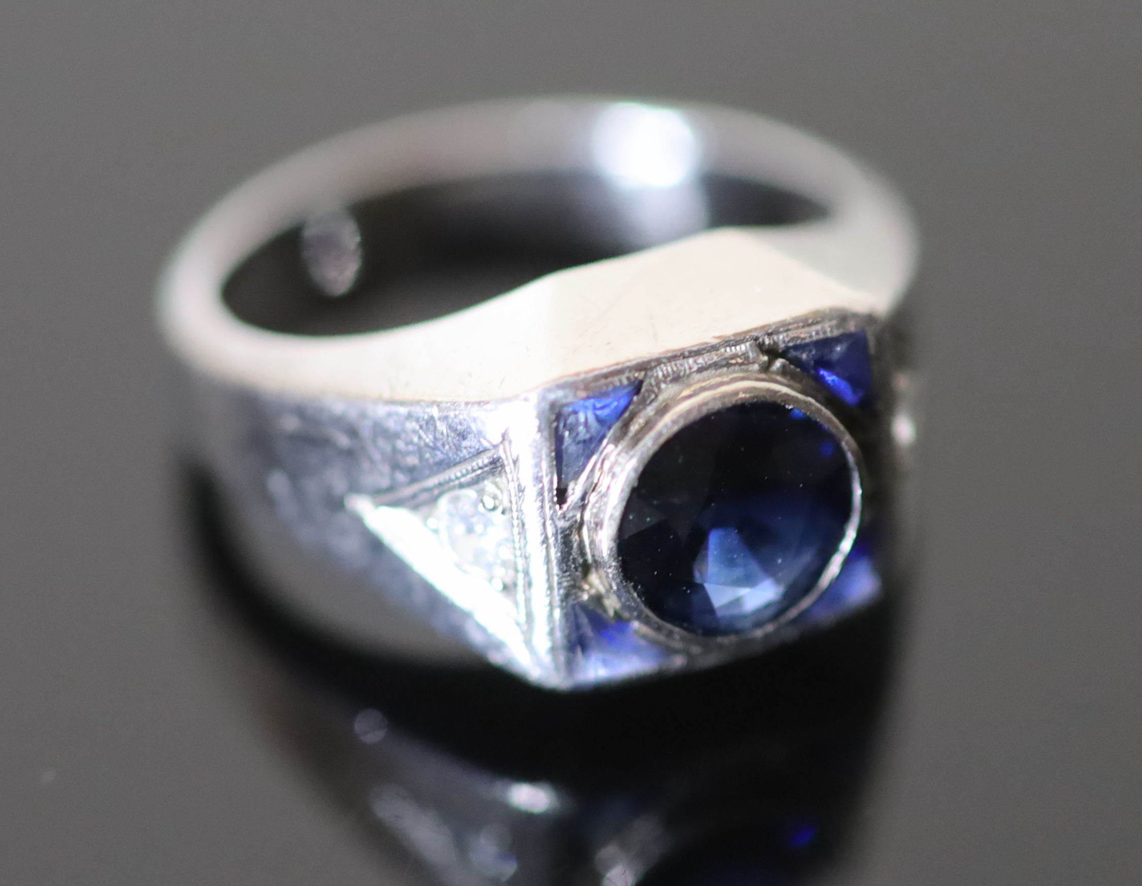 A platinum and single stone synthetic? sapphire set dress ring, with four shaped cut synthetic?