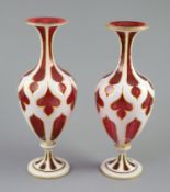 A pair of Bohemian white and ruby overlaid glass vases, the shaped panel cuts with gilded edges, the