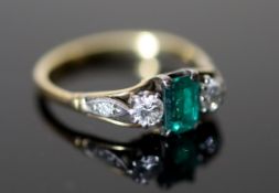 An 18ct gold, emerald and diamond set three stone ring, with diamond set shoulders, size M/N,