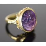A 19th century style gold ring set with an antique intaglio oval amethyst, carved with a seated