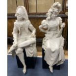 A pair of resin marble seated figures of a Dandy and a Dandizette on ebonised plinths