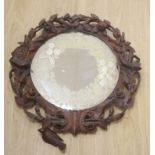 A Black Forest walnut wall mirror carved with roses, diameter 56cm