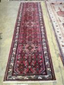 A Caucasian design red ground runner, 310 x 86cm