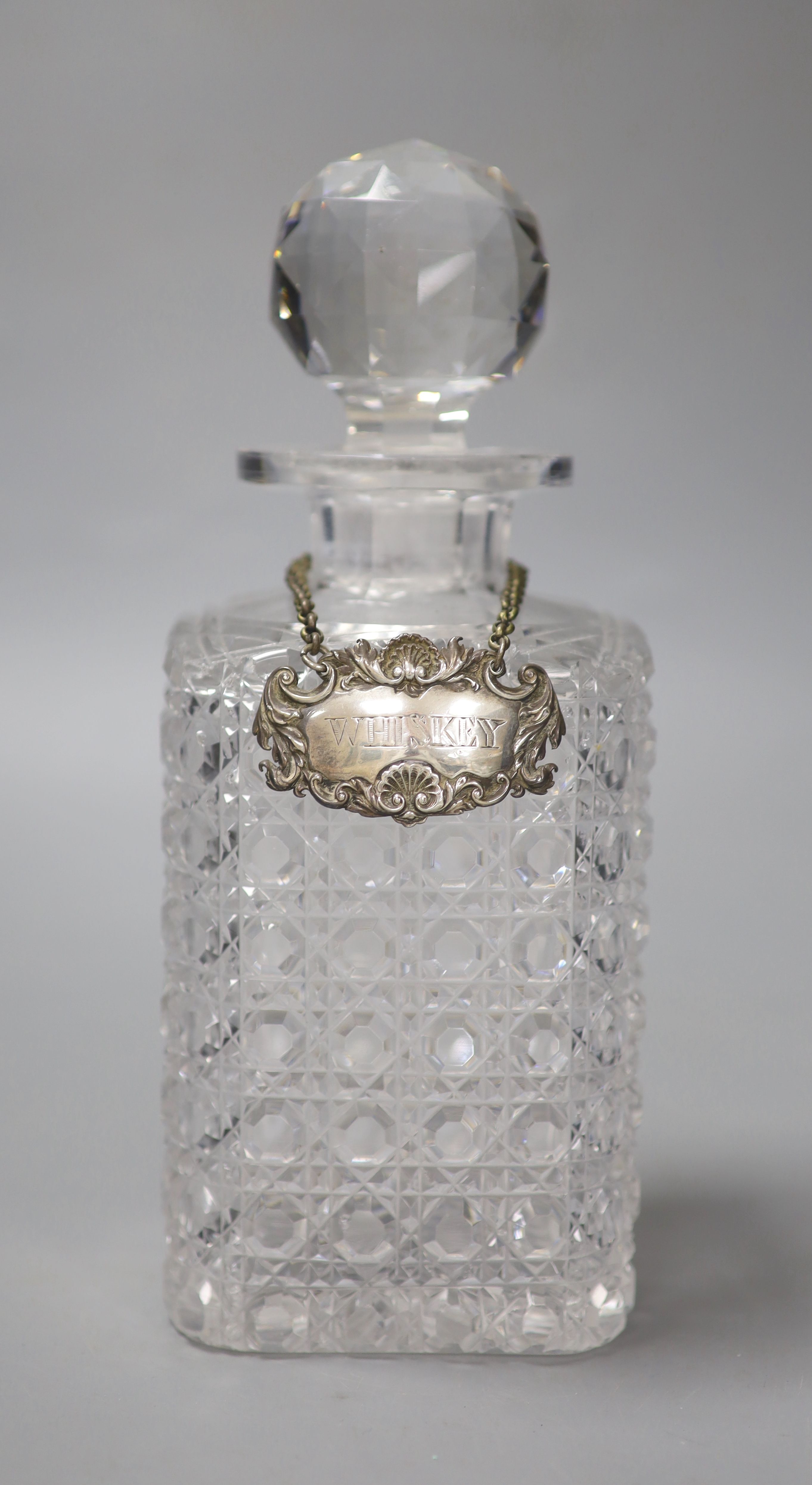 A George IV silver Whiskey label by John Riley 1824 and a cut glass decanter, height 24cm