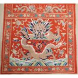 A early 20th century Chinese red felt square panel embroidered with a central motif of a dragon,