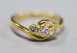 A modern 18ct gold and three stone diamond set crossover ring, size N, gross 3 grams.