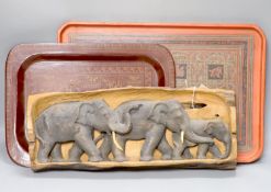 An African hardwood carving of a herd of elephants, and two papier mache trays, largest 46cm