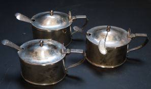 A set of three Edwardian silver mustard pots, plain oval, the hinged covers with shell