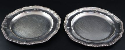 A pair of William IV silver dinner plates, with engraved crests and gadrooned border, by Robert