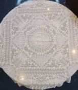 A square Normandy lace table cloth and approximately nineteen circular place mats and a centrepiece,