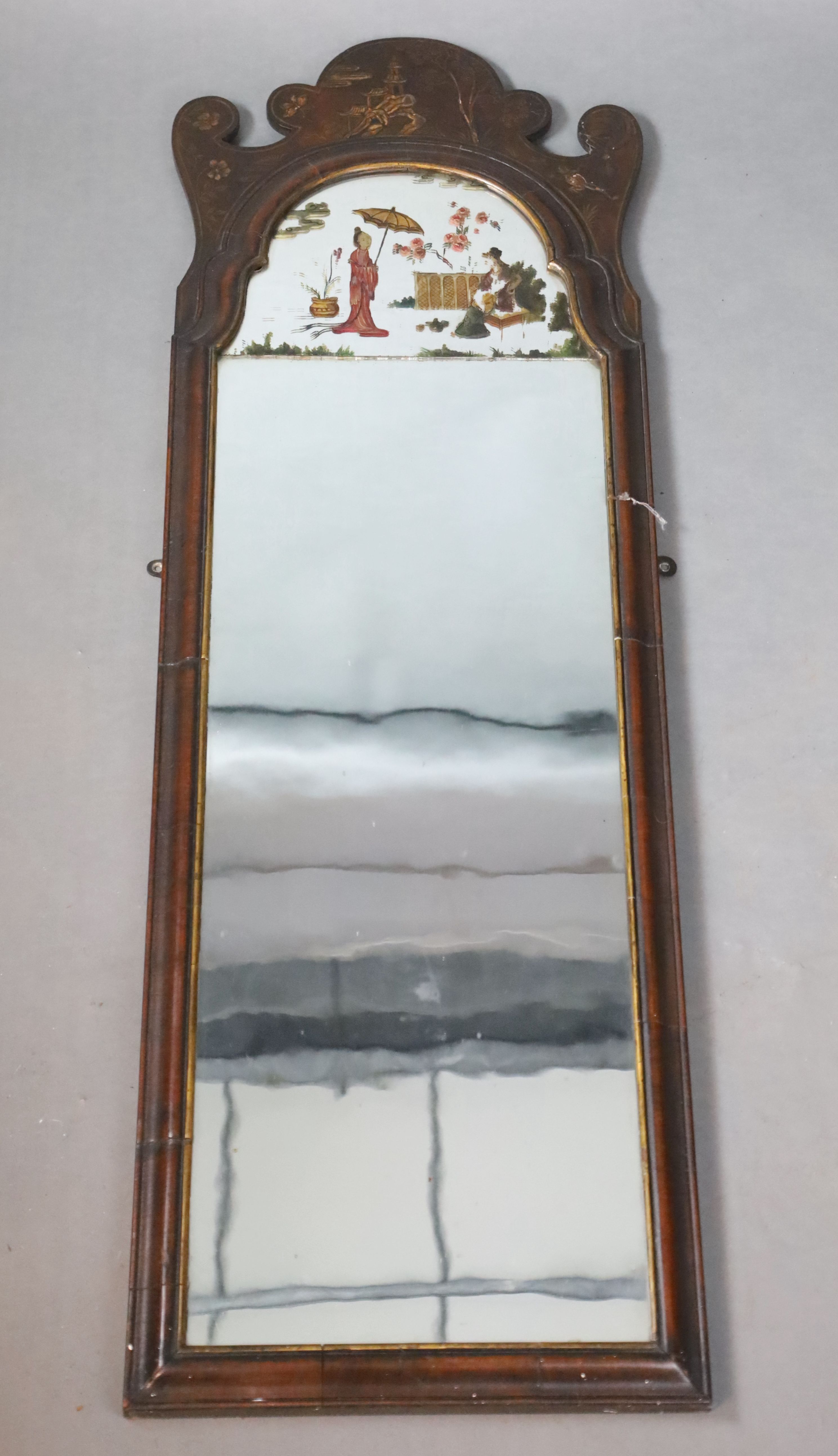 An early 18th century style chinoiserie lacquered walnut wall mirror, with chinoiserie painted glass