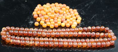 A single strand translucent amber bead necklace, 132cm, gross 153 grams and one other amber necklace