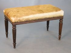 A Regency mahogany dressing stool, with padded oblong seat on turned and fluted tapered legs, W.76cm