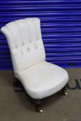 A Victorian walnut framed button back nursing chair, on turned legs, with brass and ceramic castors,