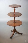 A Regency mahogany three tier dumb waiter, with drop flap base tier, on reeded tripod, fitted
