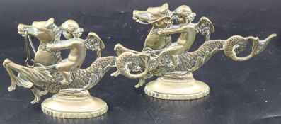 A pair of Venetian brass door stops, with cherubs riding seahorses, width 25cm height 15.