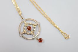 A 9ct, garnet and seed pearl set openwork circular drop pendant, 35mm, on a 9ct chain, 42cm, gross