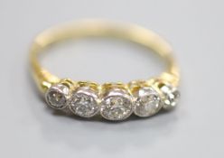 A yellow metal and graduated five stone diamond set half hoop ring, size P/Q, gross 2.6 grams.