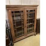 A 1920's glazed oak two door bookcase, length 130cm, depth 29cm, height 156cm