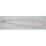 An Edwardian long silver openwork panel link and ropetwist chain tassel necklace, with mask