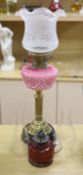 A late Victorian brass oil lamp with pink glass reservoir and a cranberry oil lamp