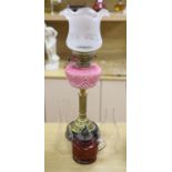 A late Victorian brass oil lamp with pink glass reservoir and a cranberry oil lamp