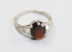 An 18ct, plat and oval garnet set dress ring with diamond set shoulders, size O, gross 2.7 grams.